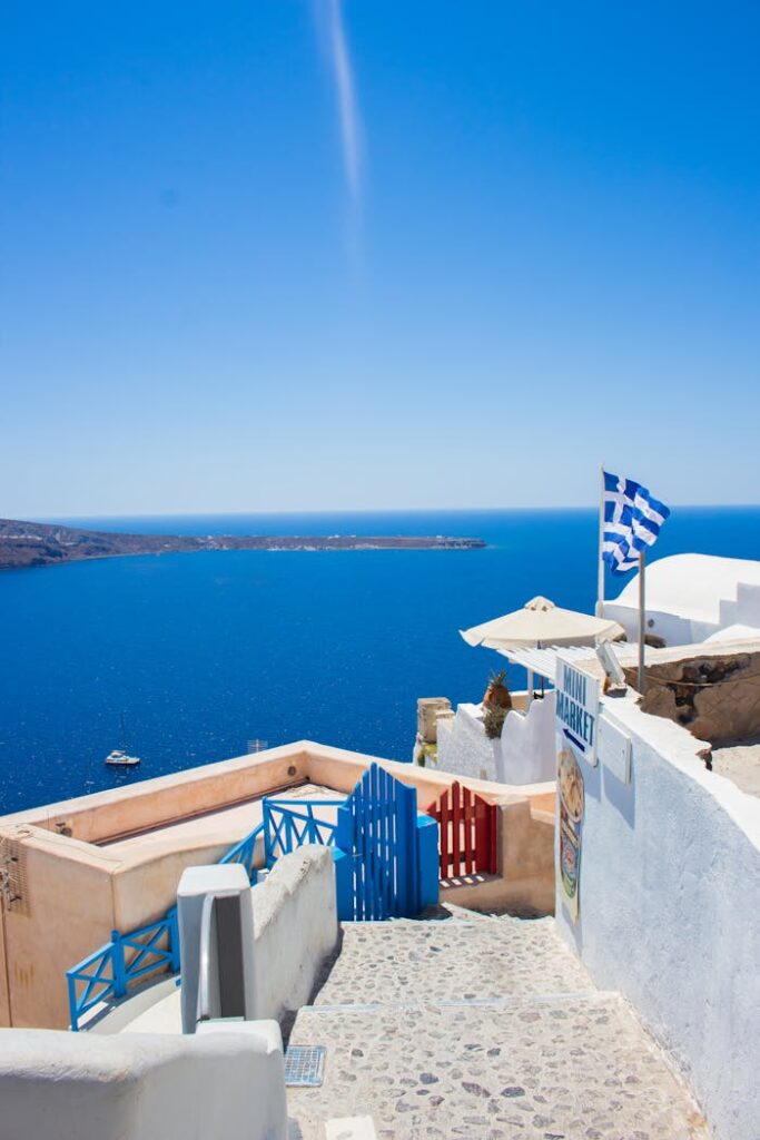 White and Blue Flag on White Concrete Wall Near Body of Water